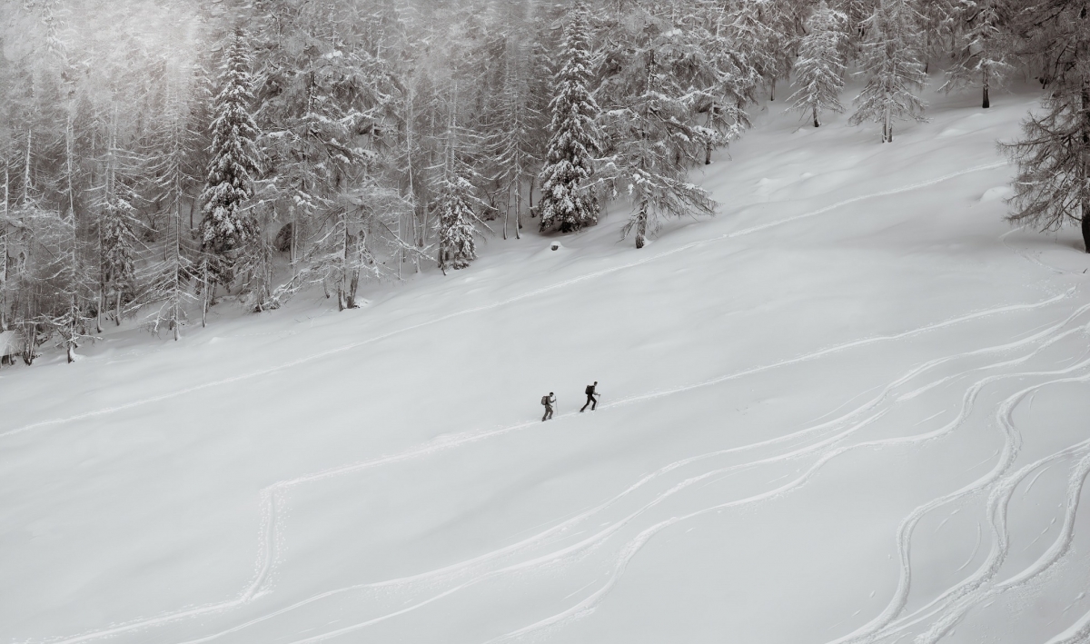 Two walkers climbing up a snow-covered mountain