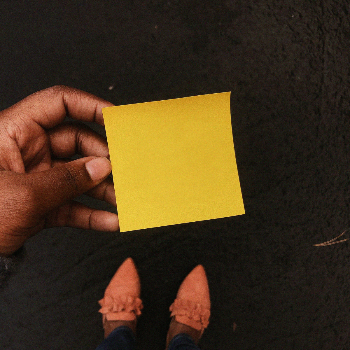 Yellow post it note being held by a person.