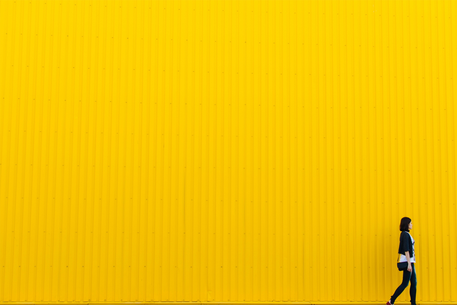Yellow plain background with one person standing to the far right.